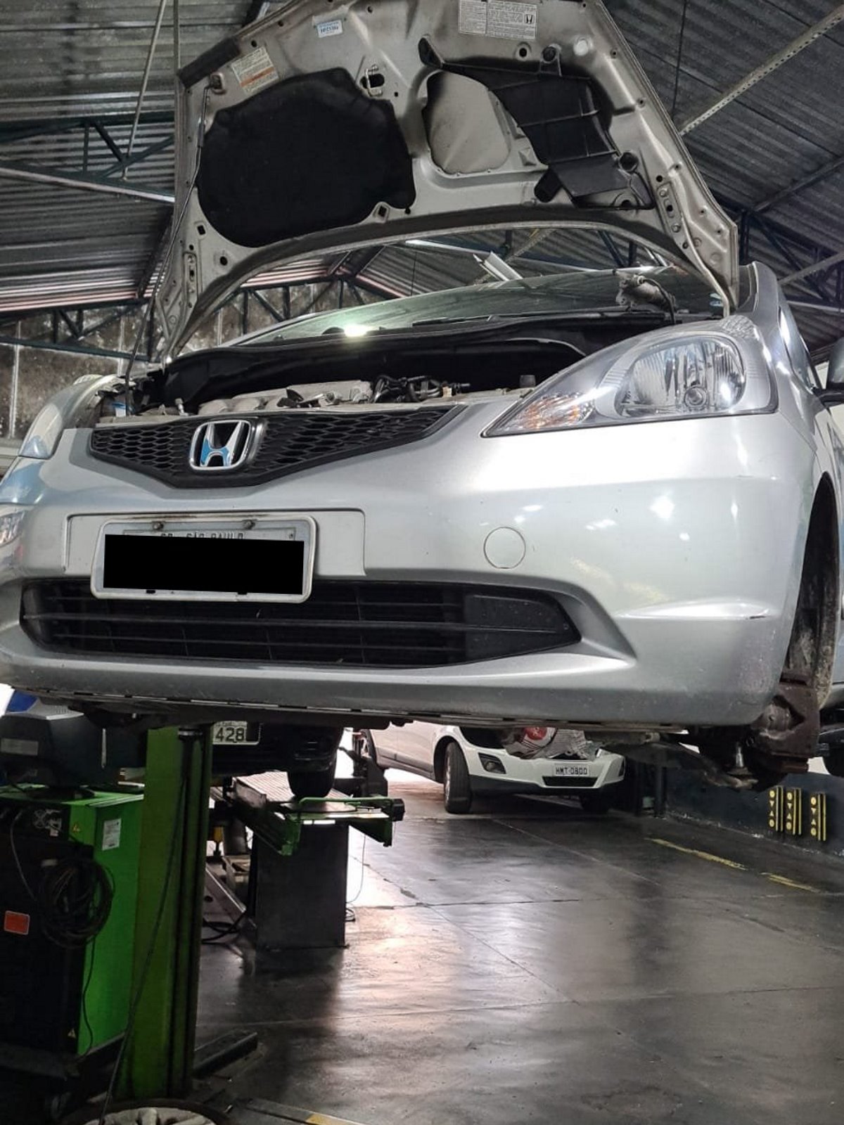Carro no elevador sendo preparado para o serviço